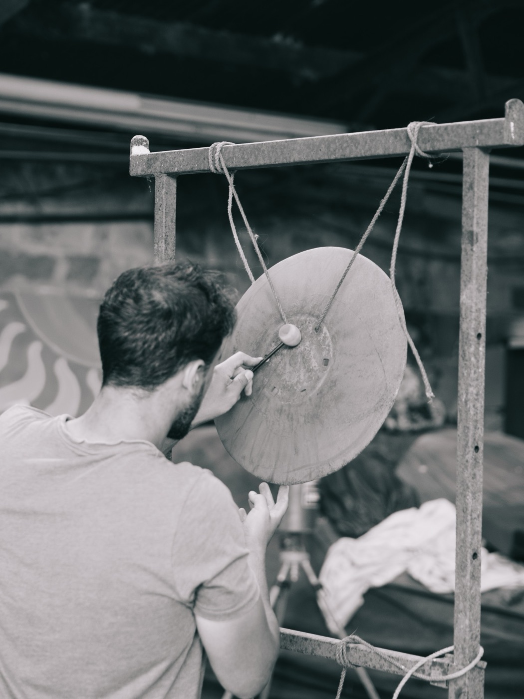 Edu Prado building the Harrowphone, striking an old harrow disc hung from a metal frame
